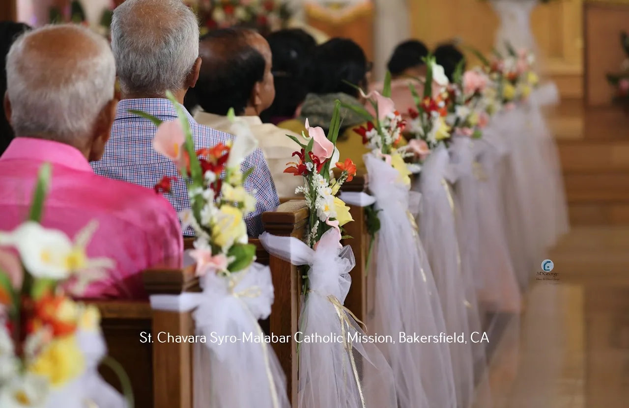 Row of wooden pews trimmed with tulle bows and flowers receding toward the sanctuary