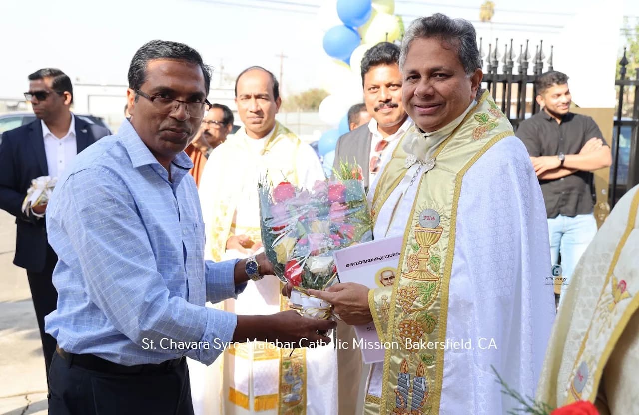 Man presenting a bouquet and booklet to a bishop in gold vestments at the church gate