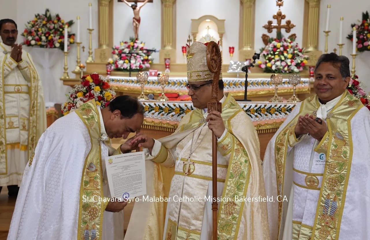 Priest kissing the bishop's hand while holding a diocesan decree at the decorated altar