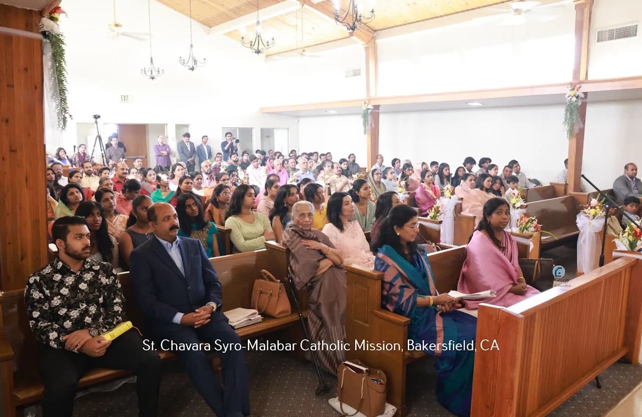 Packed congregation seated in wooden pews under a beamed ceiling during a parish service