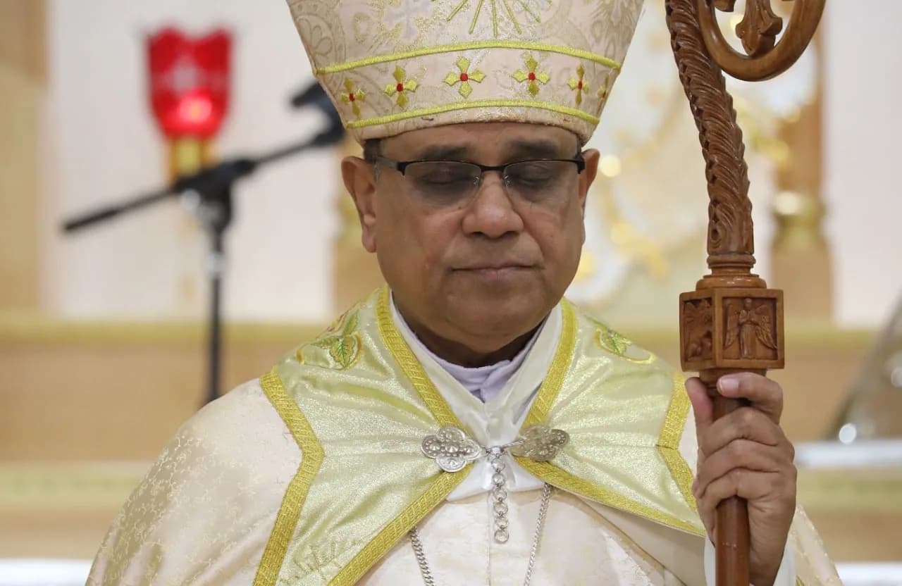 Bishop in embroidered mitre and gold vestments with eyes closed, holding a carved wooden crozier