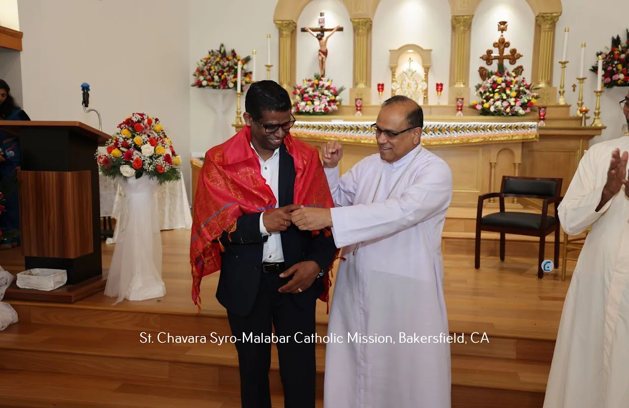 Priest draping a red ceremonial shawl over a man in a suit on the sanctuary steps