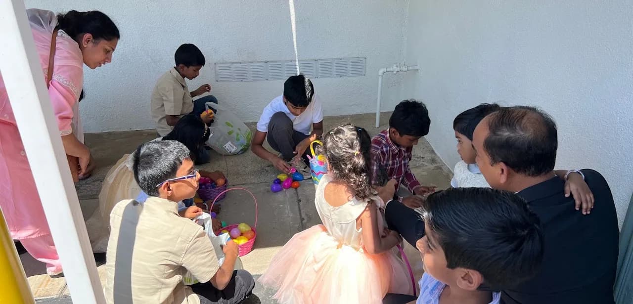 Children and adults gathering colorful plastic Easter eggs into baskets on a concrete walkway