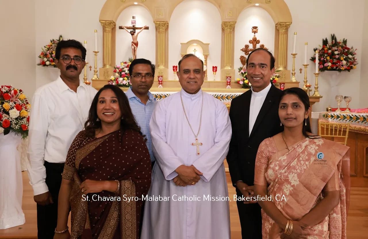 Bishop in pale cassock posing with five parishioners before a flower-decorated altar