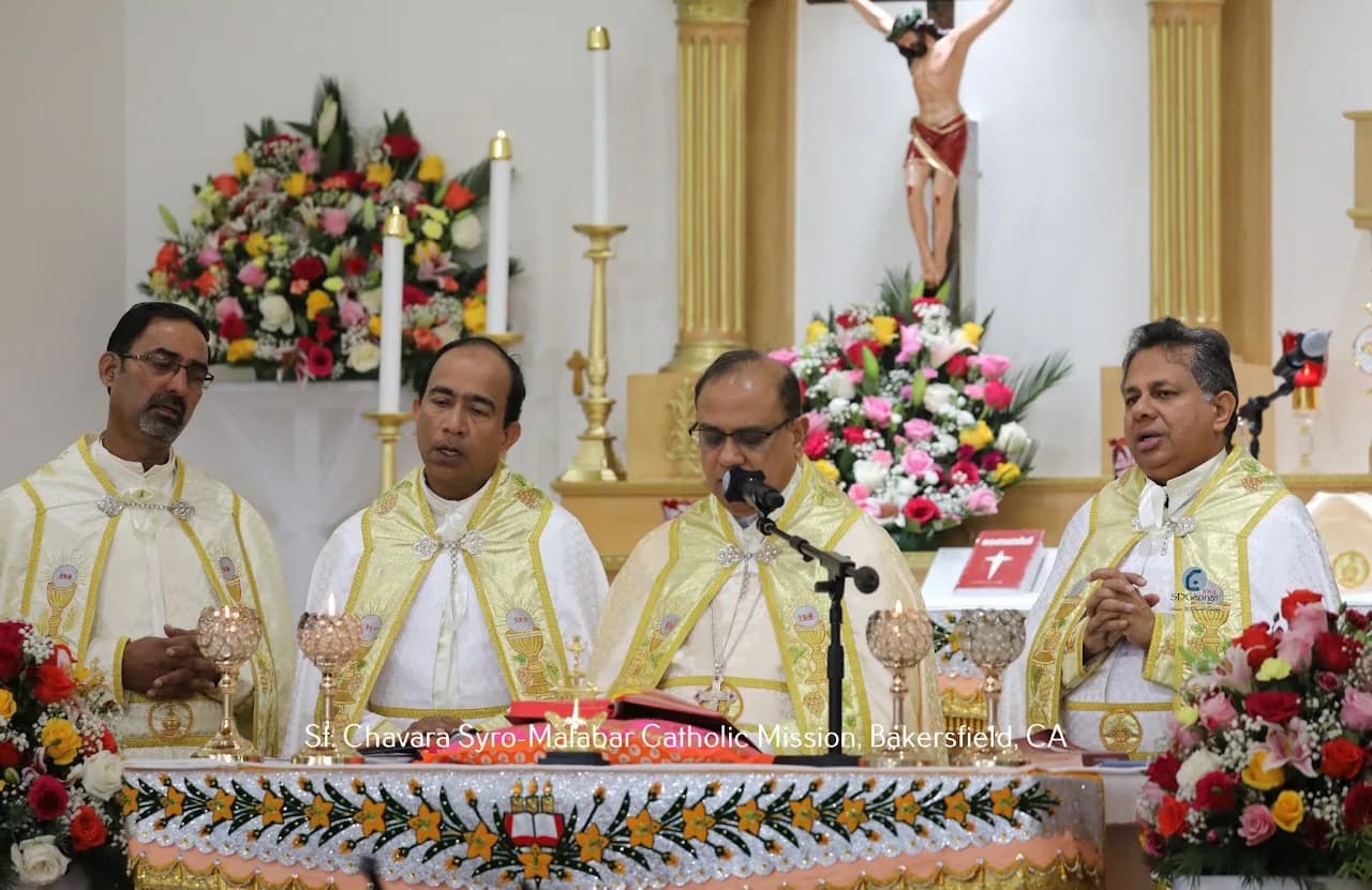 Four priests in gold vestments concelebrating at a decorated altar beneath a crucifix