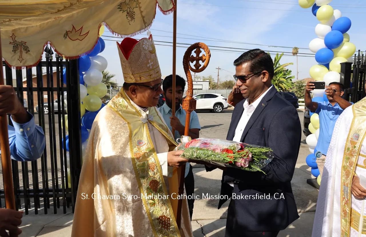 Bishop in mitre receiving a bouquet at the church gate under a ceremonial canopy and balloon arches
