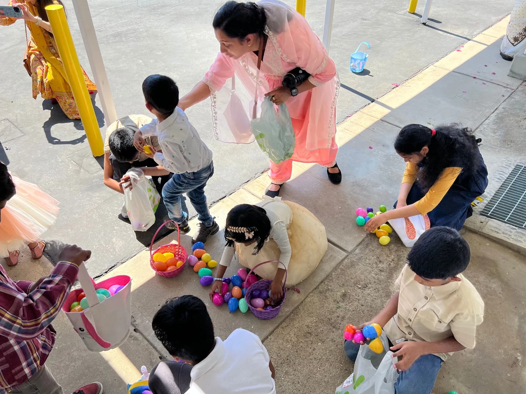 Children collecting colorful plastic eggs into baskets at a parish Easter egg hunt