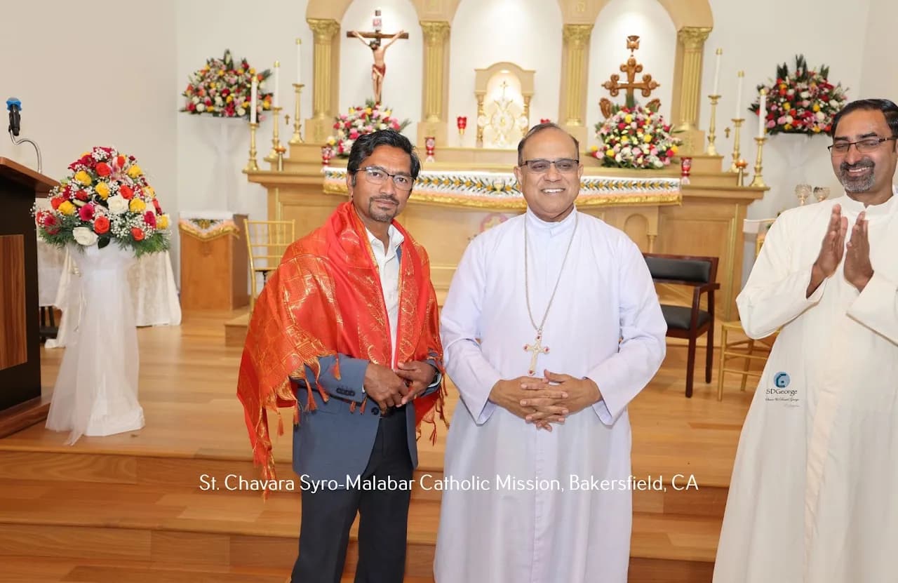 Man wearing an orange honor shawl standing with a bishop and applauding priest in the sanctuary