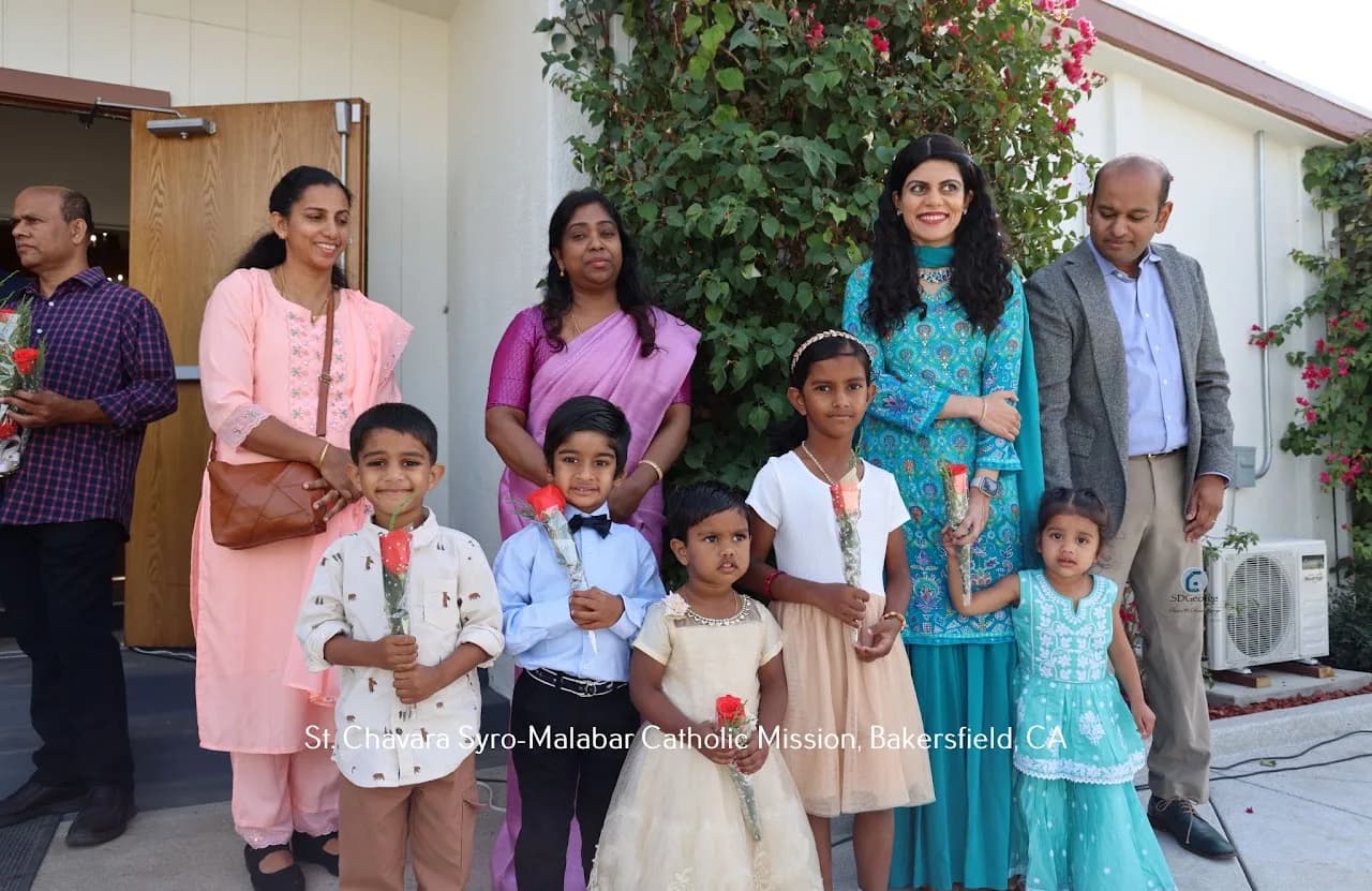 Five children holding red roses posed with adults outside the church entrance