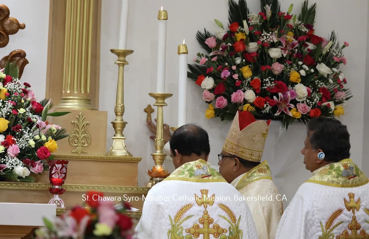 Priests and a bishop in gold vestments lighting altar candles beside large flower arrangements