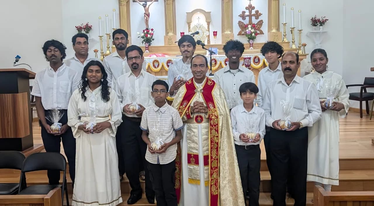 Priest in red and gold vestments with twelve parishioners holding wrapped bundles at the altar