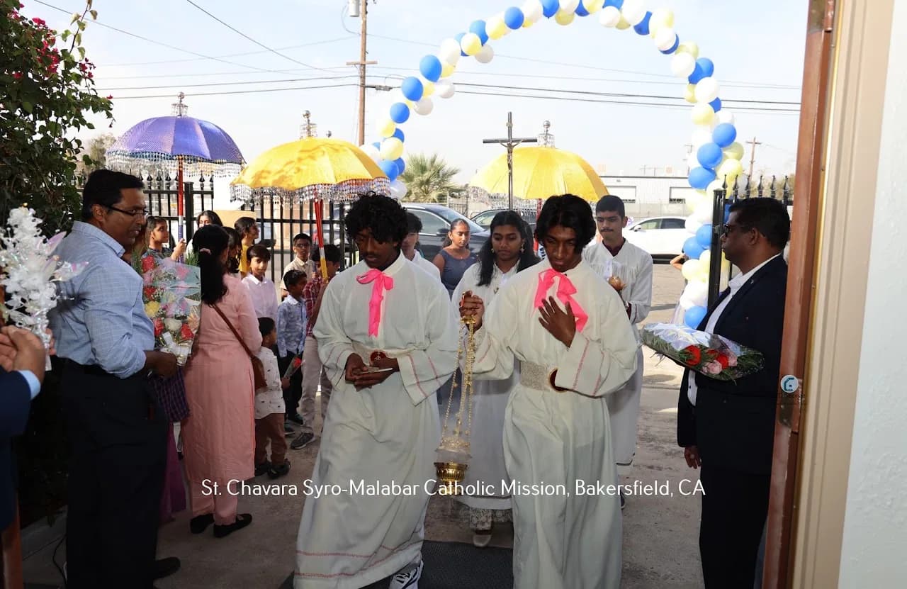Altar servers carrying a censer into church under a balloon arch with ceremonial umbrellas