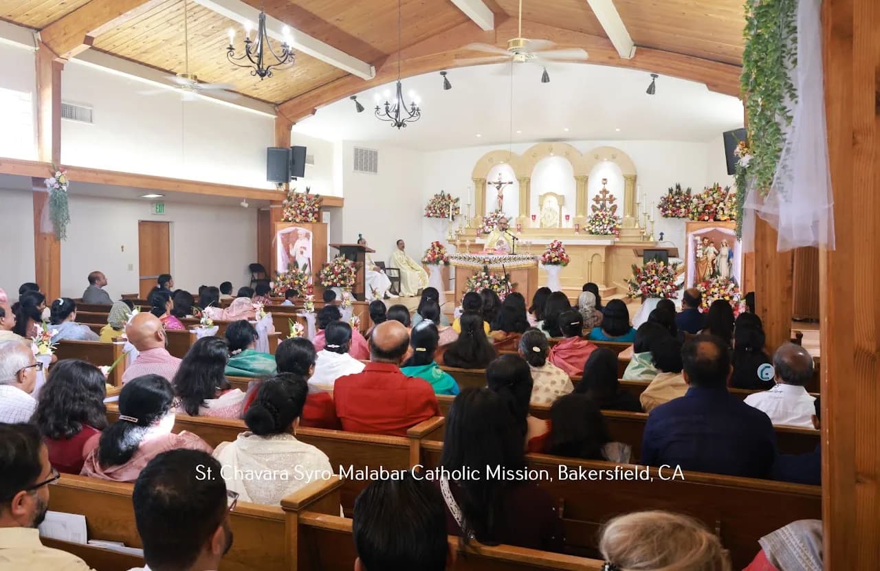 Packed church interior with about seventy worshippers in pews facing a priest at the altar