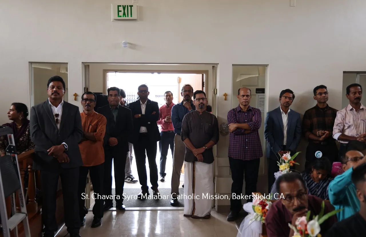 Men standing at the back of the church hall and in the open doorway during a service