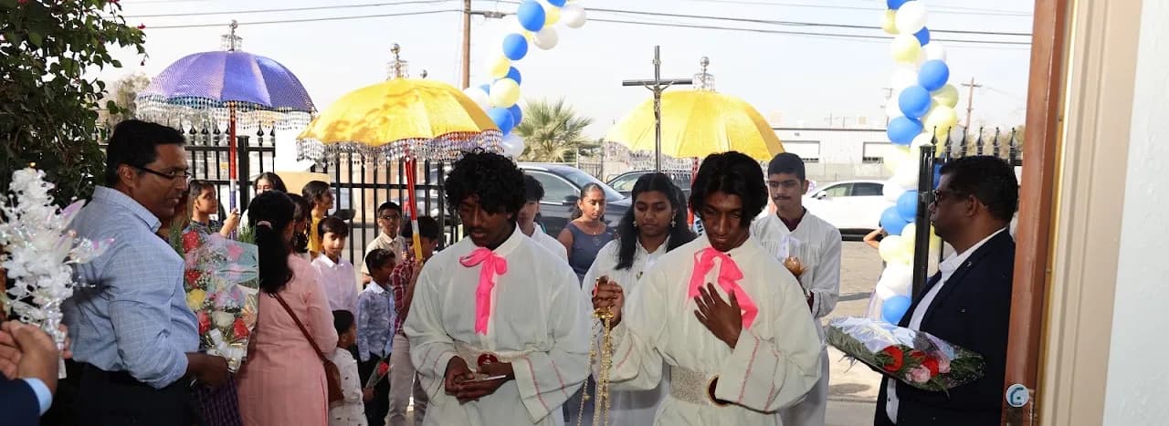 Altar servers swinging a golden thurible enter the church past ceremonial umbrellas and a balloon arch