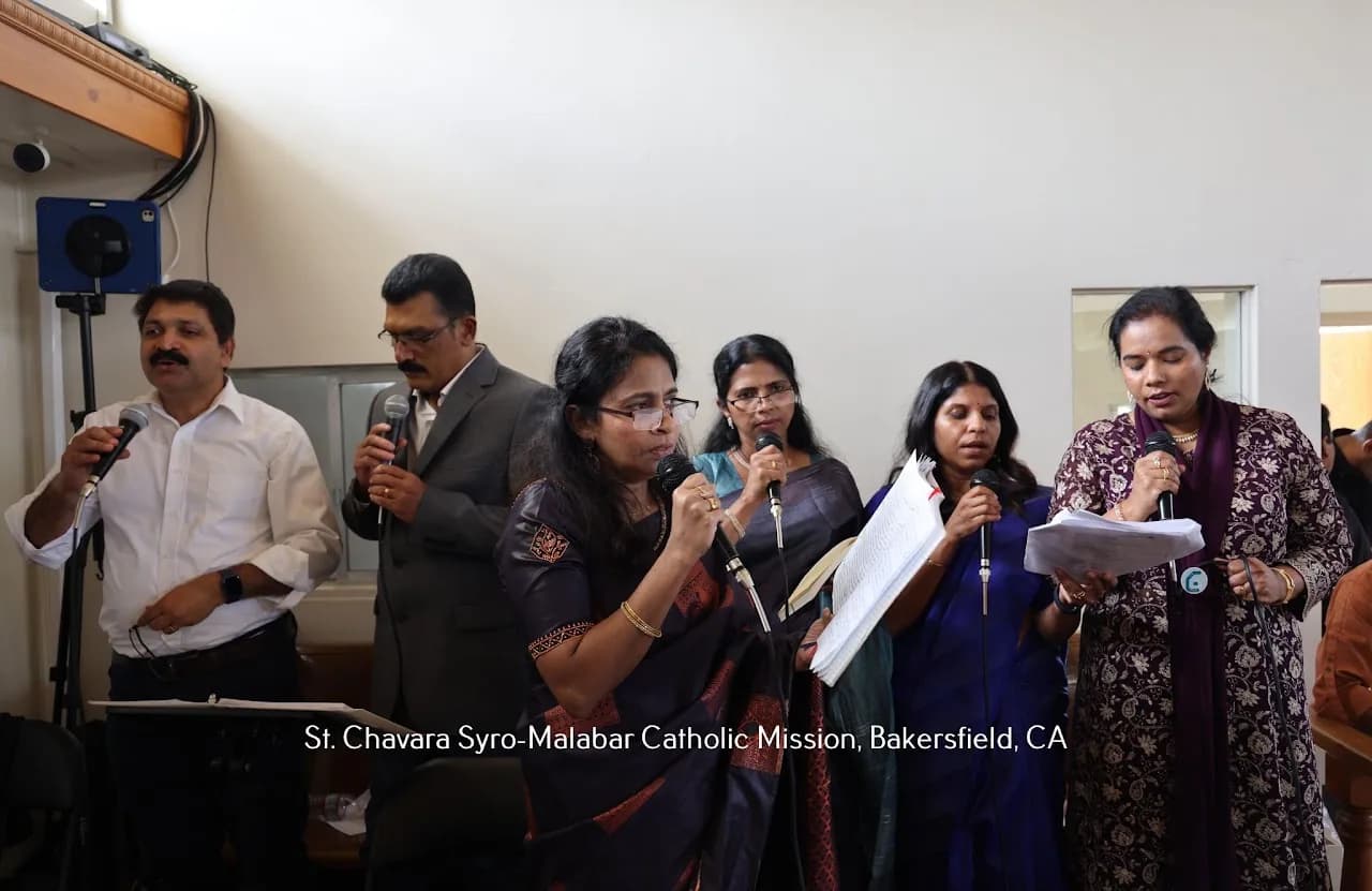 Six adult choir members singing into handheld microphones from song sheets inside the church