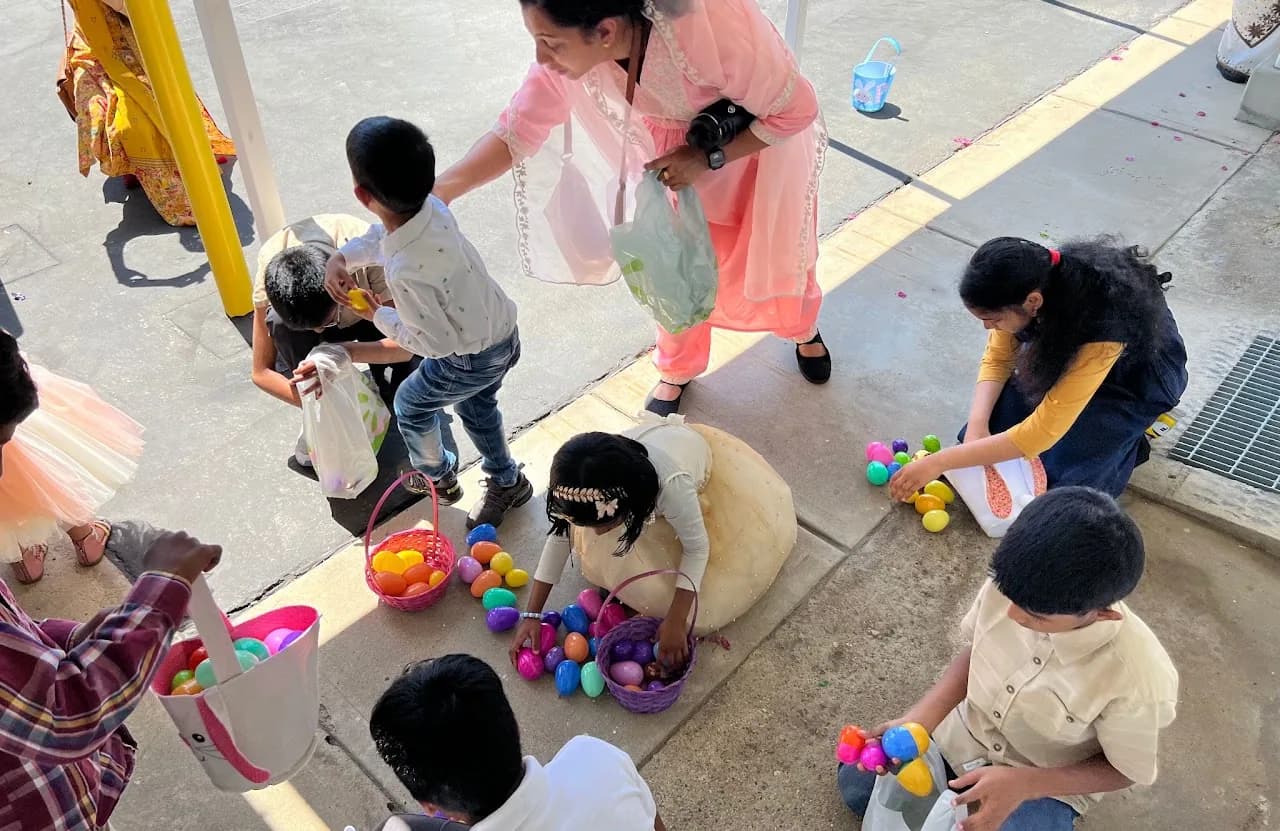 Children collecting colorful plastic Easter eggs into baskets on a sunlit walkway outside the church