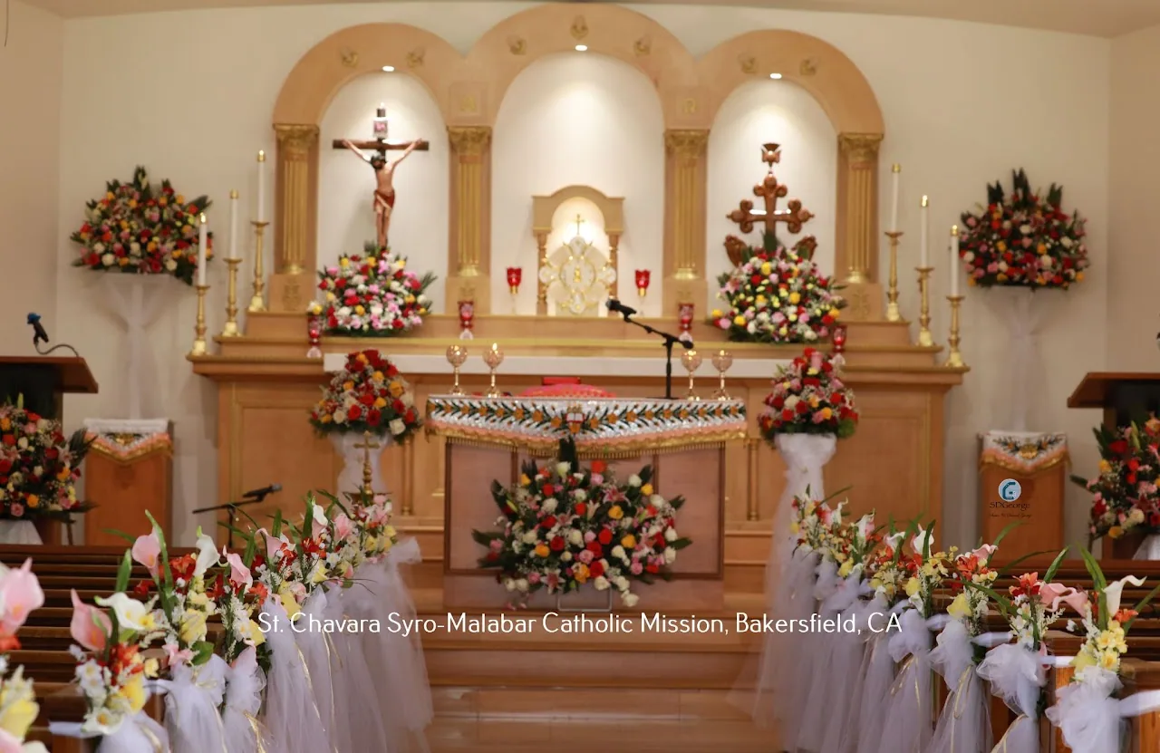 Symmetrical sanctuary view with crucifix, tabernacle, gold columns and abundant floral decorations
