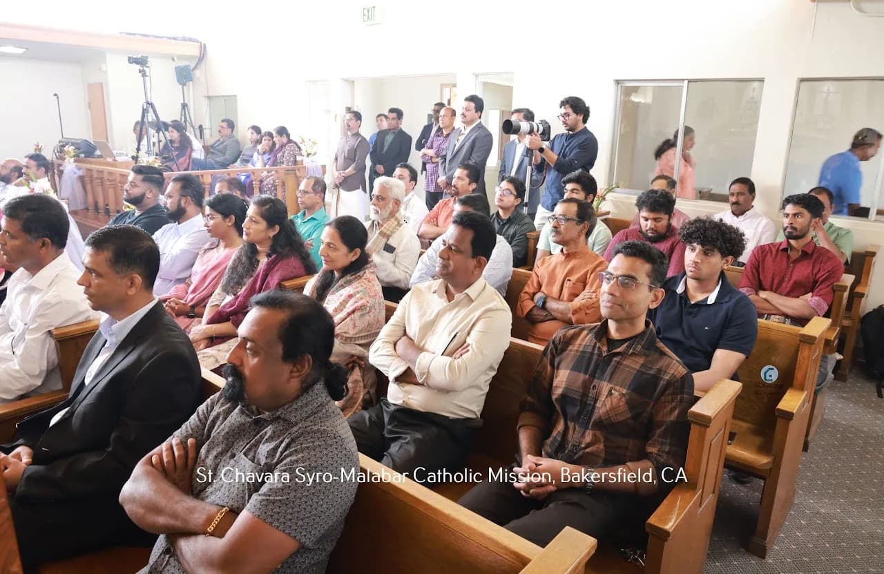 Congregation seated in wooden pews during a liturgy, with a photographer filming at the back