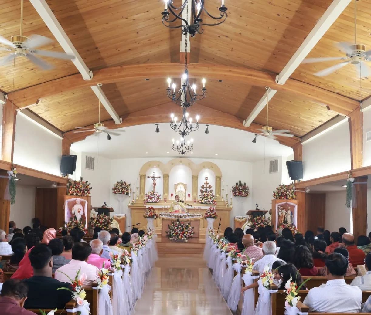 Vaulted wooden ceiling and altar of the church during a well-attended Mass