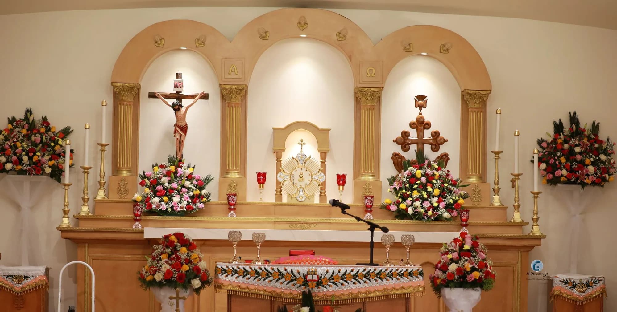 Church sanctuary with three-arched reredos, crucifix, tabernacle and rose arrangements